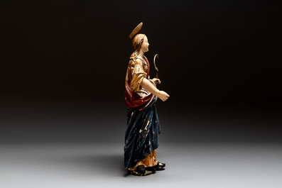 A large gilt and polychromed wooden sculpture of a female saint with a sickle, Germany, 18th C.