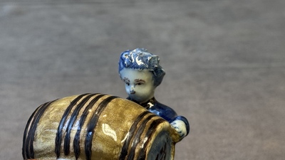 A polychrome Dutch Delft model of a boy rolling a 'wijn azijn' barrel, 18th C.
