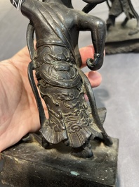 A pair of Chinese bronze guardians on stands, 17/18th C.
