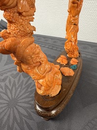 A Chinese pink-orange coral group of a goddess of spring, a wise man and children in a pine tree, 19/20th C.