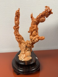 A Chinese red coral group of boys and bitter gourds on wooden stand, 19/20th C.