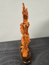 A Chinese pink-orange coral group of a goddess of spring, a wise man and children in a pine tree, 19/20th C.