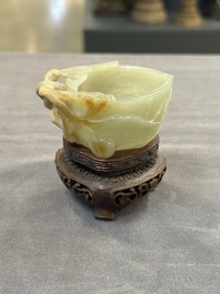 A Chinese jade peach-shaped brush washer on wooden stand, 19th C.