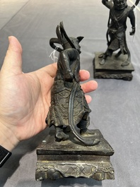 A pair of Chinese bronze guardians on stands, 17/18th C.