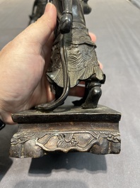 A pair of Chinese bronze guardians on stands, 17/18th C.