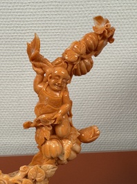 A Chinese red coral group of boys and bitter gourds on wooden stand, 19/20th C.