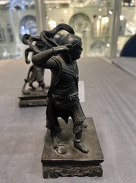 A pair of Chinese bronze guardians on stands, 17/18th C.