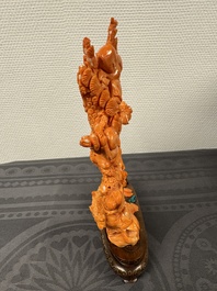 A Chinese pink-orange coral group of a goddess of spring, a wise man and children in a pine tree, 19/20th C.