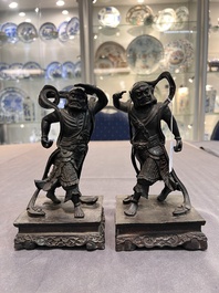 A pair of Chinese bronze guardians on stands, 17/18th C.