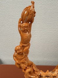 A Chinese red coral group of boys and bitter gourds on wooden stand, 19/20th C.