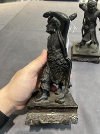 A pair of Chinese bronze guardians on stands, 17/18th C.