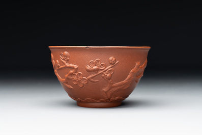 A Chinese Yixing stoneware cup and saucer with plum blossom relief design, Kangxi