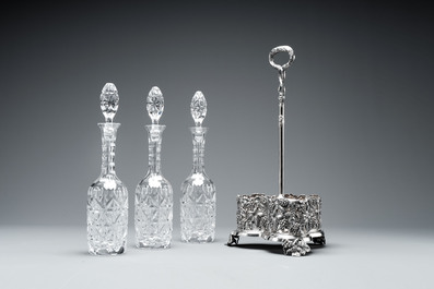 A sterling silver tantalus with three crystal-cut bottles and stoppers, 19/20th C.