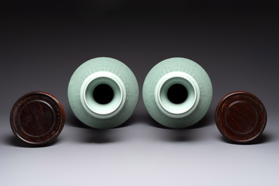 A pair of Chinese celadon-glazed vases with 'anhua' design on wooden stands, Qianlong mark, 19th C.