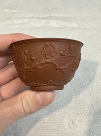 A Chinese Yixing stoneware cup and saucer with plum blossom relief design, Kangxi