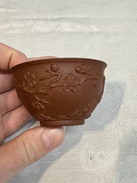 A Chinese Yixing stoneware cup and saucer with plum blossom relief design, Kangxi