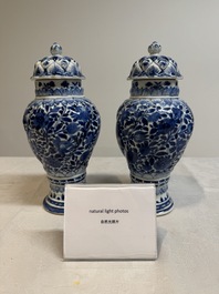 A pair of Chinese blue and white vases and covers with floral design, Kangxi