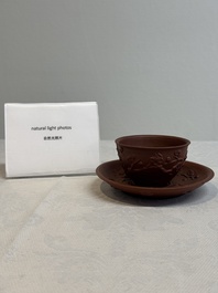 A Chinese Yixing stoneware cup and saucer with plum blossom relief design, Kangxi