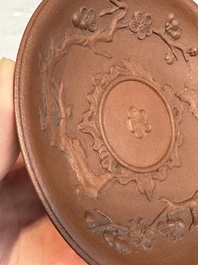 A Chinese Yixing stoneware cup and saucer with plum blossom relief design, Kangxi