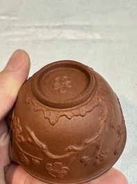 A Chinese Yixing stoneware cup and saucer with plum blossom relief design, Kangxi