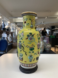 A pair of Chinese famille rose yellow-ground relief-decorated vases with wooden stands, 19th C.