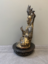 A Chinese parcel-gilt bronze Guanyin and wooden stand, Ming