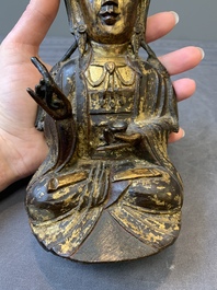 A Chinese parcel-gilt bronze Guanyin and wooden stand, Ming