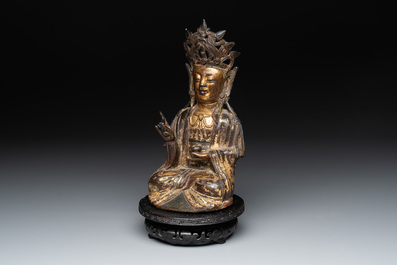 A Chinese parcel-gilt bronze Guanyin and wooden stand, Ming