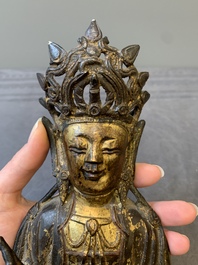 A Chinese parcel-gilt bronze Guanyin and wooden stand, Ming