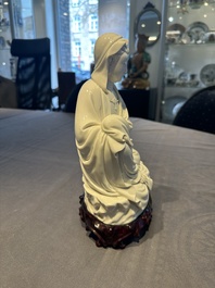 A Chinese Dehua blanc de Chine figure of a seated Guanyin on wooden stand, 19/20th C.