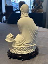 A Chinese Dehua blanc de Chine figure of a seated Guanyin on wooden stand, 19/20th C.