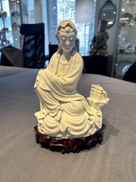 A Chinese Dehua blanc de Chine figure of a seated Guanyin on wooden stand, 19/20th C.