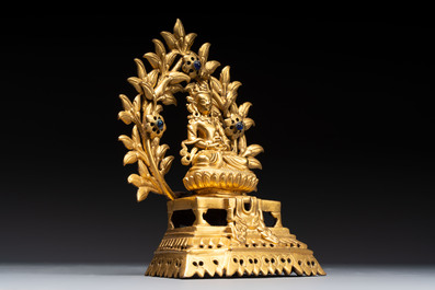 A Nepalese gilt-bronze Buddha on an inscribed throne with a mandorla, 19th C.