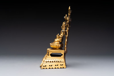 A Nepalese gilt-bronze Buddha on an inscribed throne with a mandorla, 19th C.
