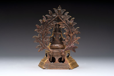 A Nepalese gilt-bronze Buddha on an inscribed throne with a mandorla, 19th C.