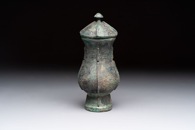 A Chinese archaic bronze food vessel and cover with taotie design, 'zhi 觶', Shang