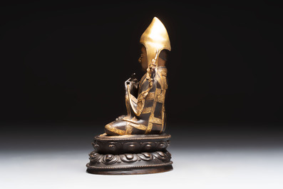 A Tibetan parcel-gilt bronze sculpture of a lama, 20th C.