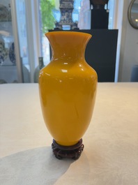 A Chinese Peking yellow glass vase on wooden stand, 19th C.
