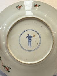 A Chinese famille rose octagonal dish and a famille verte plate with figures in a landscape, ding mark, Kangxi/Qianlong