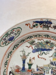 A Chinese famille rose octagonal dish and a famille verte plate with figures in a landscape, ding mark, Kangxi/Qianlong