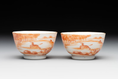 A pair of Chinese iron-red-decorated 'deer hunting' cups and saucers, Qianlong