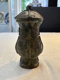 A Chinese archaic bronze food vessel and cover with taotie design, 'zhi 觶', Shang