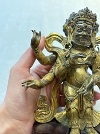 A Sino-Tibetan gilt-bronze figure of White Mahakala on wooden stand, 18th C.