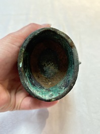 A Chinese archaic bronze food vessel and cover with taotie design, 'zhi 觶', Shang