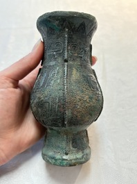 A Chinese archaic bronze food vessel and cover with taotie design, 'zhi 觶', Shang