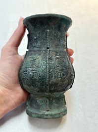 A Chinese archaic bronze food vessel and cover with taotie design, 'zhi 觶', Shang