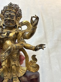 A Sino-Tibetan gilt-bronze figure of White Mahakala on wooden stand, 18th C.