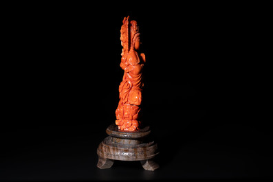 A fine Chinese red coral sculpture of Guanyin seated on a lotus throne on a wooden stand, 19/20th C.