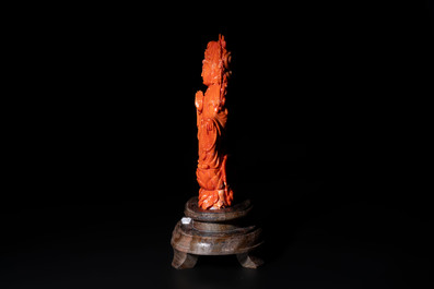 A fine Chinese red coral sculpture of Guanyin seated on a lotus throne on a wooden stand, 19/20th C.