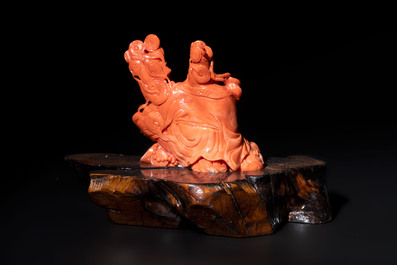 A Chinese red coral sculpture of a Milefo Buddha on wooden stand, 19/20th C.